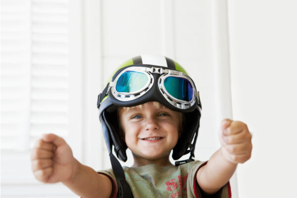 Noordhoek, South Africa --- Young boy wearing helmet pretending to drive a car --- Image by © Bruno Obmann/Corbis